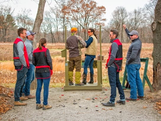 Happy shooters holding up their targets at an indoor range