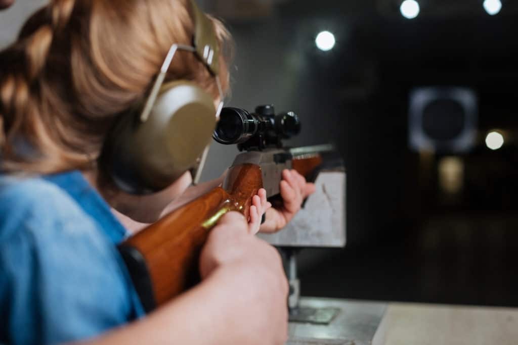 Woman aiming rifle at target downrange